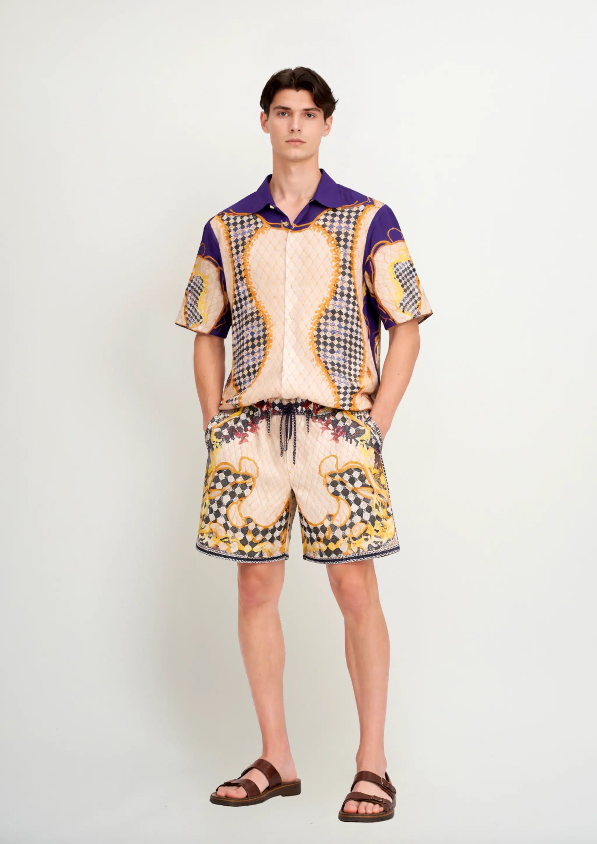 Model in studio wearing a luxury men's resortwear co-ord set by Korè Collections, featuring the short-sleeve resort shirt and matching swim trunks in the exclusive Blooming Night geometric print.