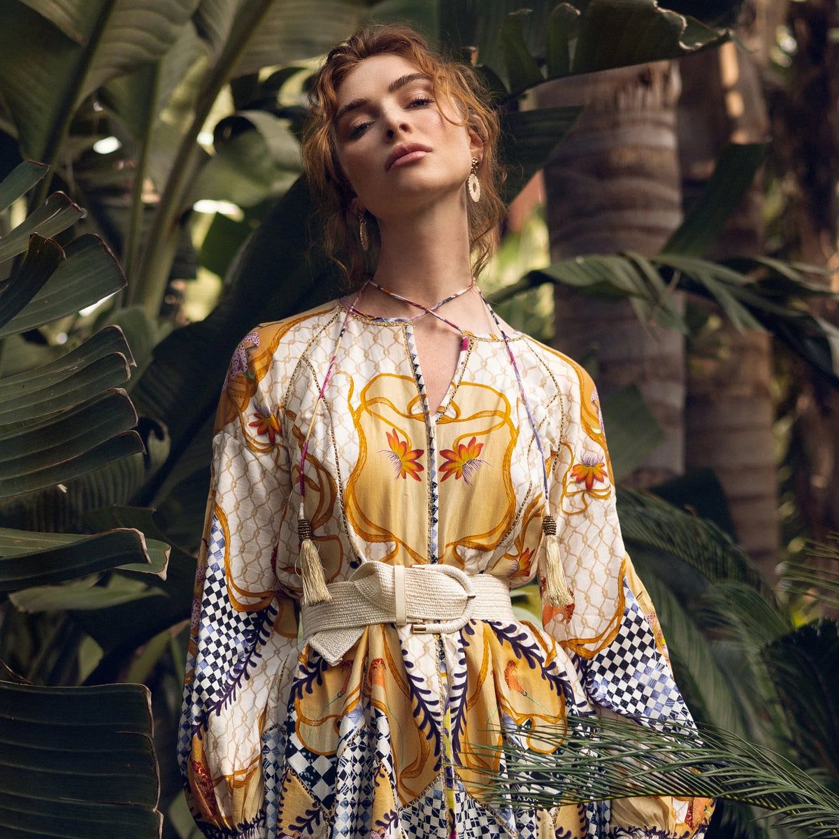 Woman in a patterned dress standing among tropical plants