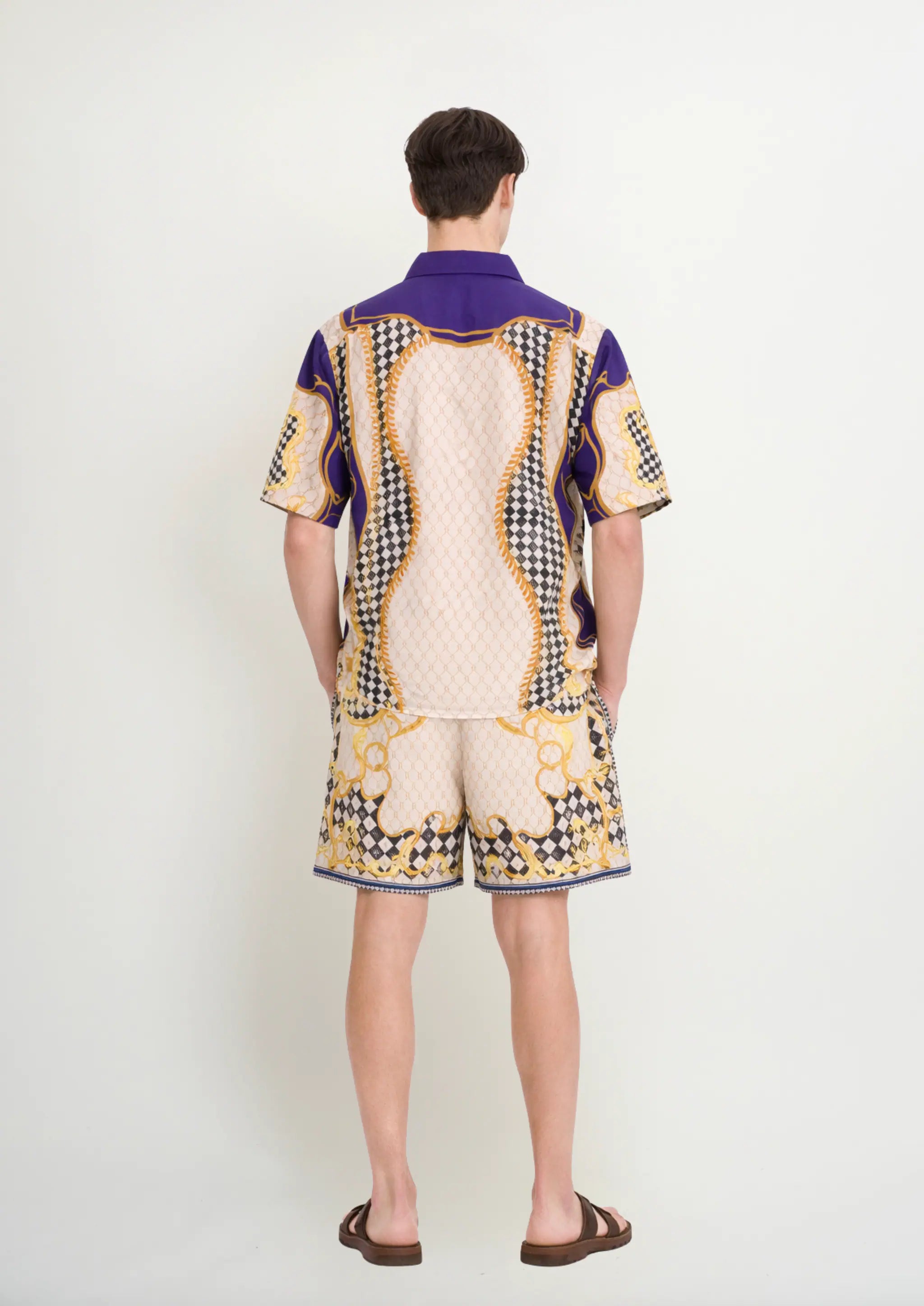 Back view of a model wearing a luxury men's resortwear co-ord set by Korè Collections, highlighting the precision graphic placement and comfortable cut of the Blooming Night shirt and matching swim shorts.